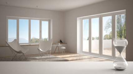White table or shelf with crystal hourglass measuring the passing time over modern living room with panoramic window, architecture interior design, copy space background