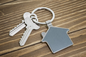 keychain with house symbol and keys on wooden background,Real estate concept
