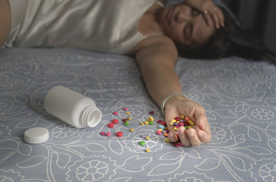 Asian middle-aged woman in nightgown dress commit suicide by taking a lot of pills in the bedroom
