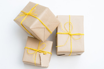 assortment of presents wrapped in craft paper tied with a yellow twine. holiday gifts on christmas or new year. three packages on white background with copyspace.