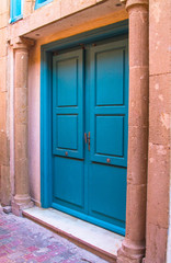 The old wooden door is blue in the background of the plastered peeling wall. Moroccan style. Africa, Morocco, Essaouira