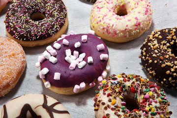 assorted donuts with chocolate frosted, pink glazed and sprinkles donuts