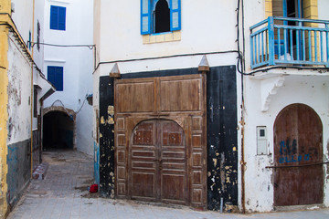 An old, covered wooden door against the backdrop of a stone peeling wall. Moroccan style. Africa, Morocco, Essaouira