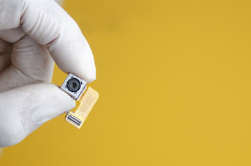 Hand with rubber gloves holding smartphone camera lens part