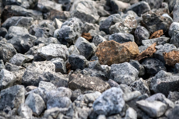 stones average size mostly dark gray and several red, on the ground, texture, background, photo in the street in daylight, close-up