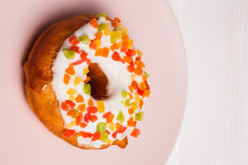 donut in sugar glaze with candied fruits on a pink plate