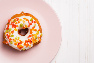 donut in sugar glaze with candied fruits on a pink plate