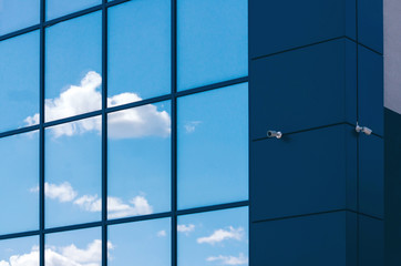 Glass facade of modern office building with security camera
