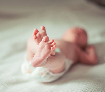 health concept - closeup of legs of a newborn baby lying on whit