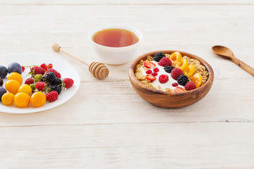 granola with berries on white wooden background