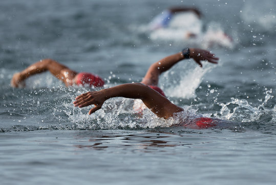 Swimmers swimming crawl in blue sea, contest triathlon