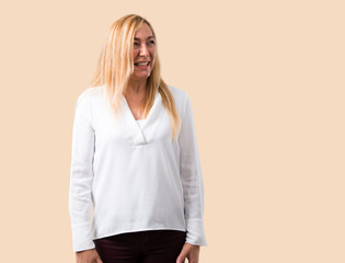 Middle age blonde woman with white shirt is a little bit nervous and scared pressing the teeth on...
