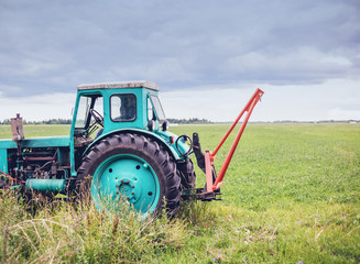 Old green tractor on the background of a rural field, beautiful rural farm landscape