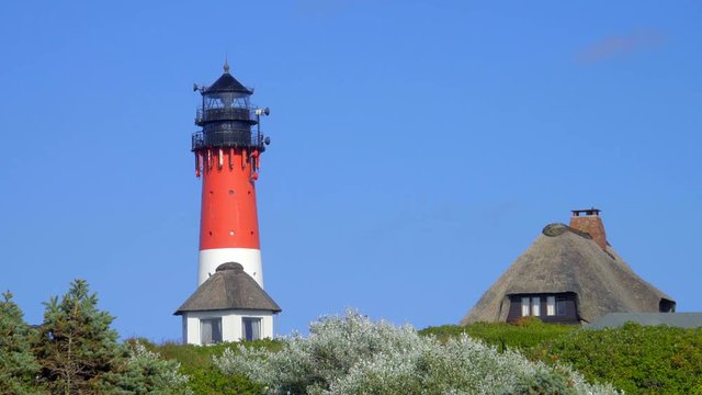 Leuchtturm H&ouml;rnum Sylt mit D&uuml;nen Landschaft  Reetdach H&auml;usern und  blauen Himmel
