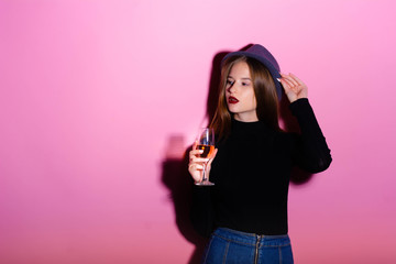 Aperol. Girl drinks alcohol. Aperitif. Girl with a bright makeup. Pink background. Style. Image. Blue hat