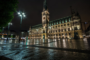 Fototapeta na wymiar Hamburg City Hall is the seat of local government of the Free and Hanseatic City of Hamburg, Germany. Amazing reflections on the ground. Wet nasty weather.