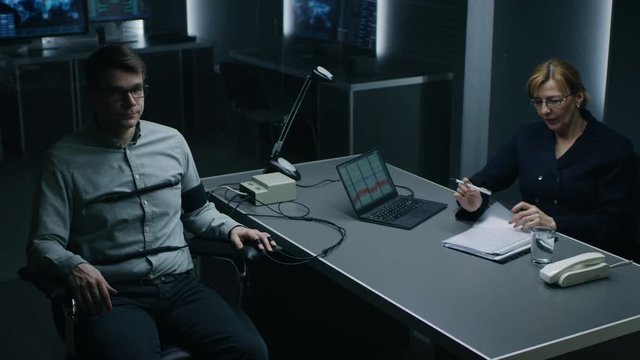 Female Special Agent Conducts Lie Detector / Polygraph Test on a Young Suspect. Expert Examiner Asks Accused Yes or No Questions in Interrogation Room. Computer Records Reactions.