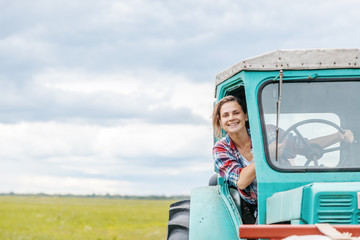 Young beautiful girl working on a tractor in the field, unusual work for women, gender equality...