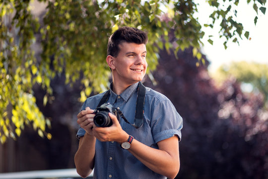 Young professional male photographer using camera at street