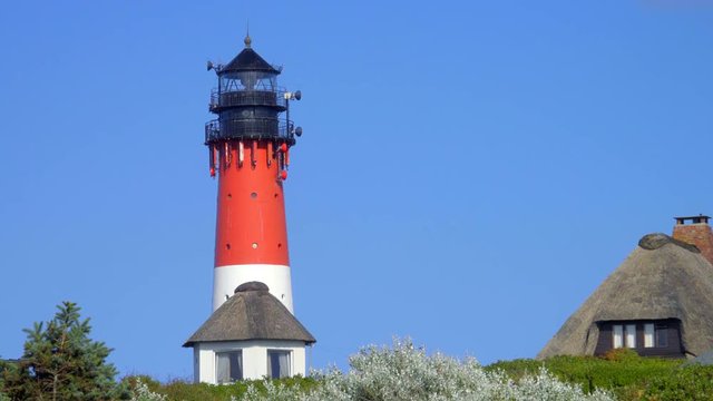 Leuchtturm H&ouml;rnum Sylt mit D&uuml;nen Landschaft  Reetdach H&auml;usern und  blauen Himmel
