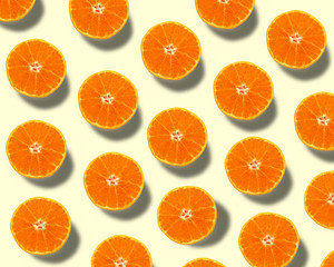 Summer pattern made of fresh orange cut in half on yellow background.