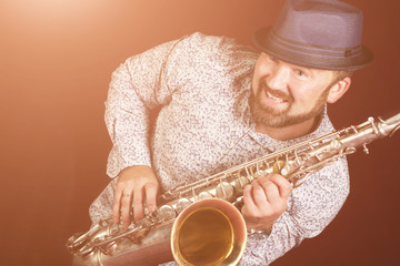 A young man in a hat playing the saxophone.