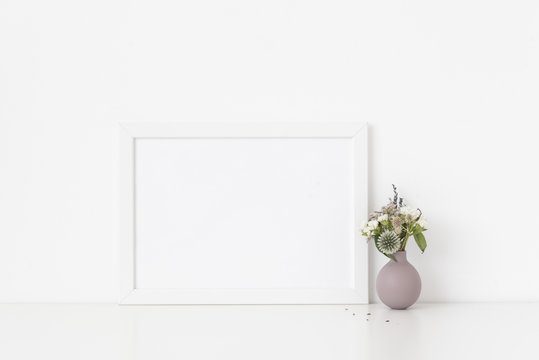 White a4 landscape portrait frame mockup with bouquet of dried flowers in cute small vase on white wall background. Empty frame, poster mock up for presentation design. 