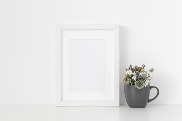 White A5 portrait frame mockup with dried field wild flowers in gray mug on white wall background. Empty frame, poster mock up for presentation design. Template frame for text, lettering, modern art.