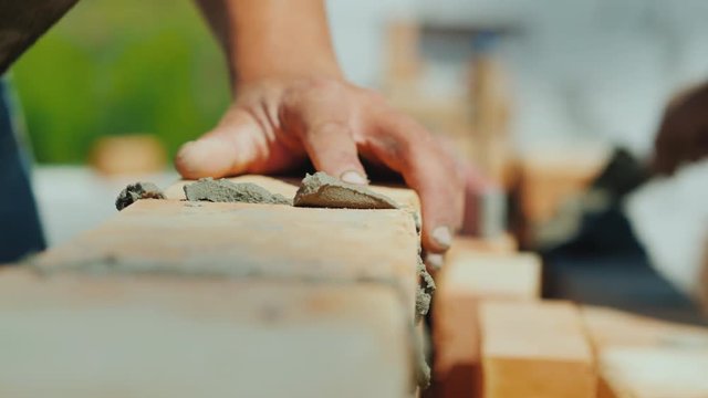 Two specialist builders build a house of brick, a close-up of hands with a brick