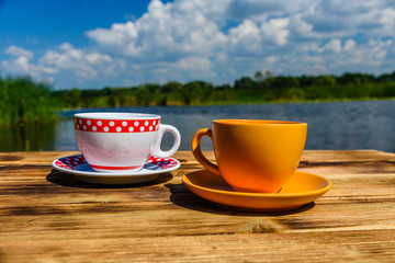 Two cups of coffee on wooden table at the riverside
