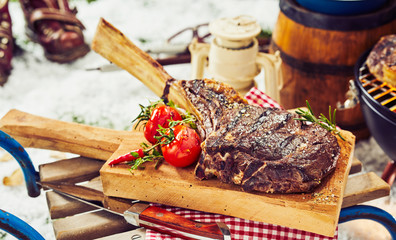 Thick steak and tomatoes on cutting board