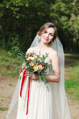 Fototapeta na wymiar Beautiful bride with bouquet outdoors in a forest