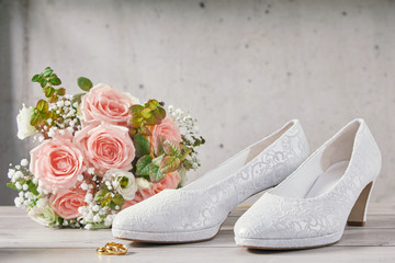 Bouquet of pink roses next to wedding shoes