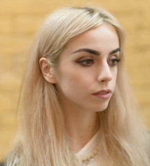 Portrait of a beautiful blonde girl on yellow brick background.