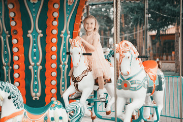 Obraz na płótnie Canvas little girl riding in the Park on a toy horse on the carousel