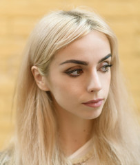 Portrait of a beautiful blonde girl on yellow brick background.