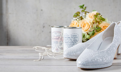 Obraz na płótnie Canvas Bridal shoes next to cans and flower bouquet