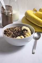 Bowl of homemade granola with banana, cocoa and carob