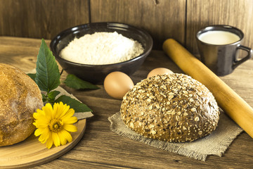 Food, breakfast. Rustic still life. Fresh bread baked in the bakery, chicken eggs, cottage cheese and milk on the background of the texture of a wooden table