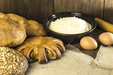 Food. Rustic still life. Fresh bread baked in a bakery, chicken eggs and cottage cheese on a background of a wooden table texture
