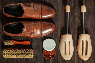Leather shoes with accessories for cleaning arranged on a wooden board