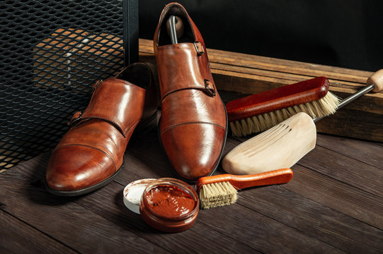 Leather shoes and shoe polish equipment on a wooden composition
