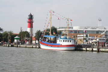 Hafeneinfahrt von Büsum in Deutschland an der Nordsee mit Leuchturm Wasser und Schiffen