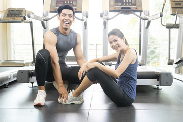 Fototapeta na wymiar Attractive young fitness couple resting on floor in the gym.