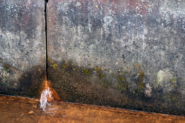 two concrete slabs of dirty gray color in spots, rusty water flows from the hole from below, in the foreground there is a liquid rusty from corrosion, a gloomy look, design, background, daylight,