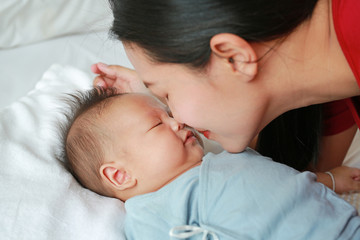 Obraz na płótnie Canvas Close up mother kissing baby boy lying on the bed.