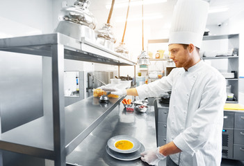 food cooking, profession and people concept - happy male chef cook with plate of soup and salad at restaurant kitchen table