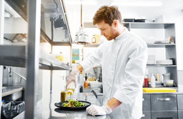 food cooking, profession and people concept - happy male chef cook making vegetable salad at restaurant kitchen