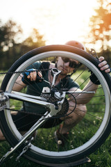 Bike repair. Young man repairing mountain bike in the field