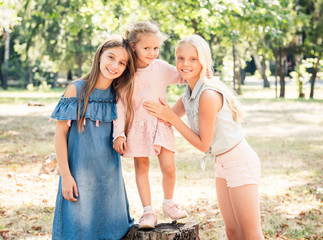 Little girls stand hugging in a sunshine autumn park